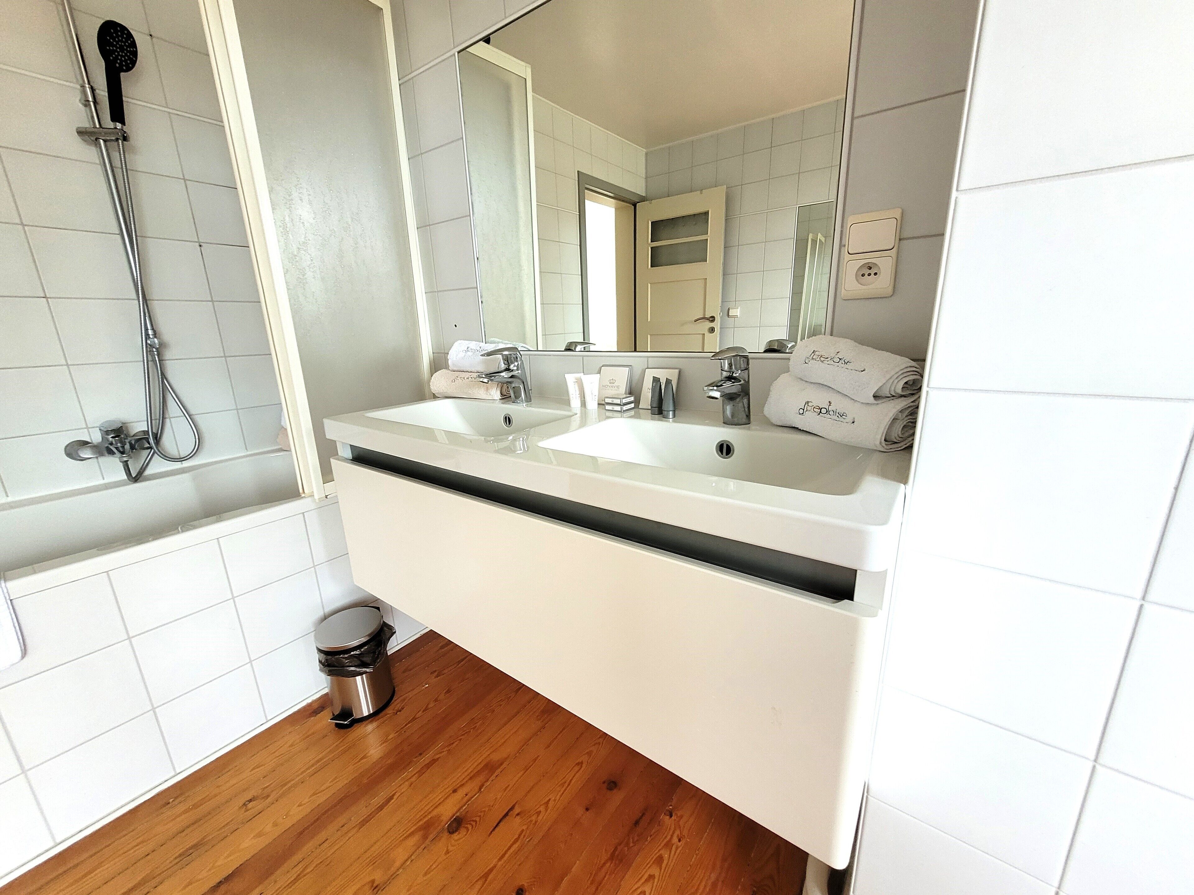 Un baño con un lavabo blanco, un espejo y una ducha.