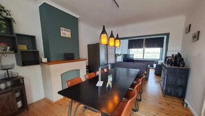 A dining area with a long table, chairs, and a hanging light fixture. - Vakantiehuis d'Ereplatse (Zuienkerke)