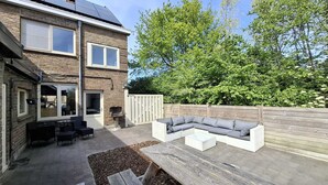 A backyard with a wooden deck, a built-in sectional sofa, and a barbecue grill. - Vakantiehuis d'Ereplatse (Zuienkerke)