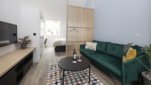 Una sala de estar moderna con un sofá verde, una mesa de centro de madera y un televisor sobre un mueble de madera.