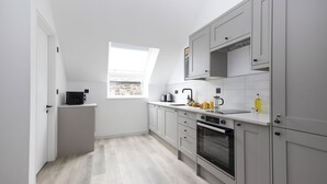 Una cocina moderna con gabinetes grises, horno empotrado y ventana que proporciona luz natural.