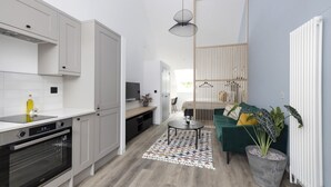 Una cocina moderna con armarios blancos, horno empotrado y comedor con mesa y sillas.
