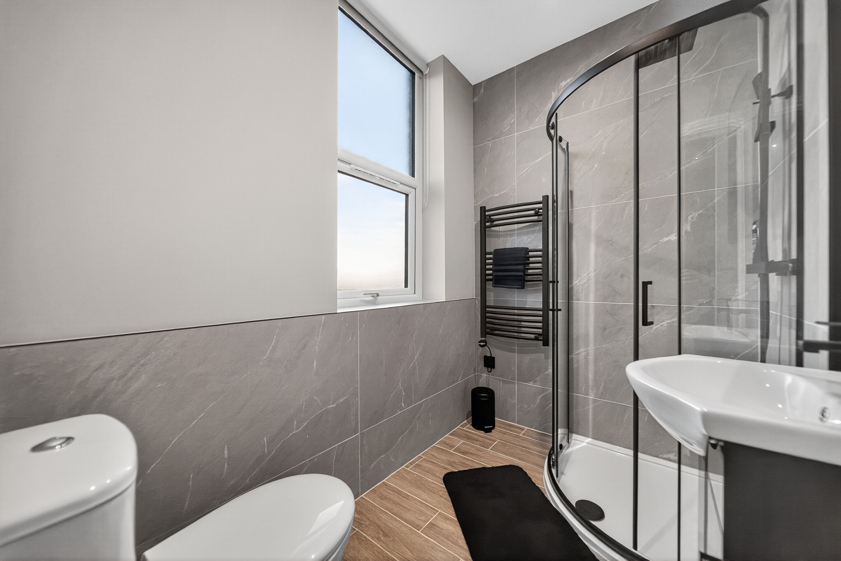 Un baño moderno con inodoro, ducha con puerta de vidrio y lavamanos.