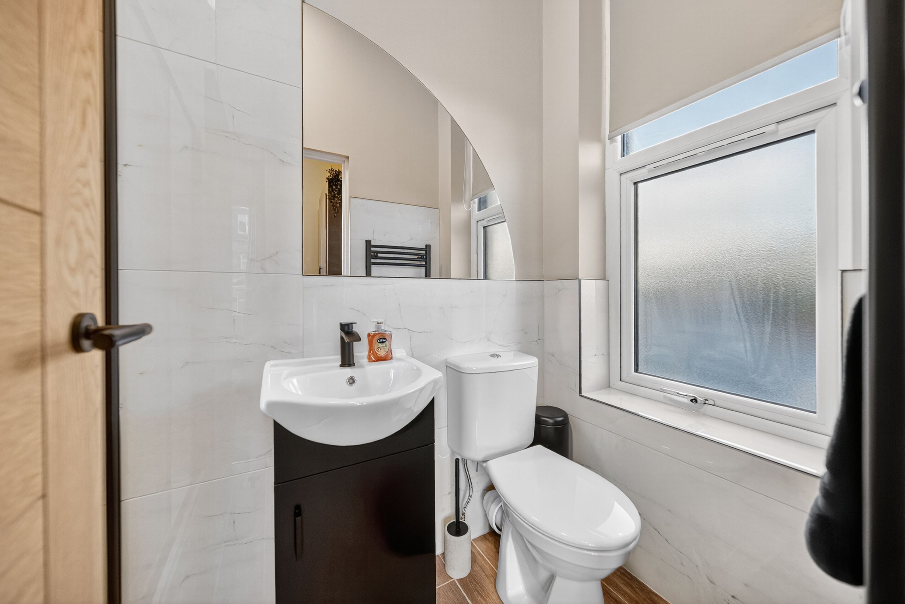 Un bany modern amb un vàter blanc, un lavabo i una finestra.