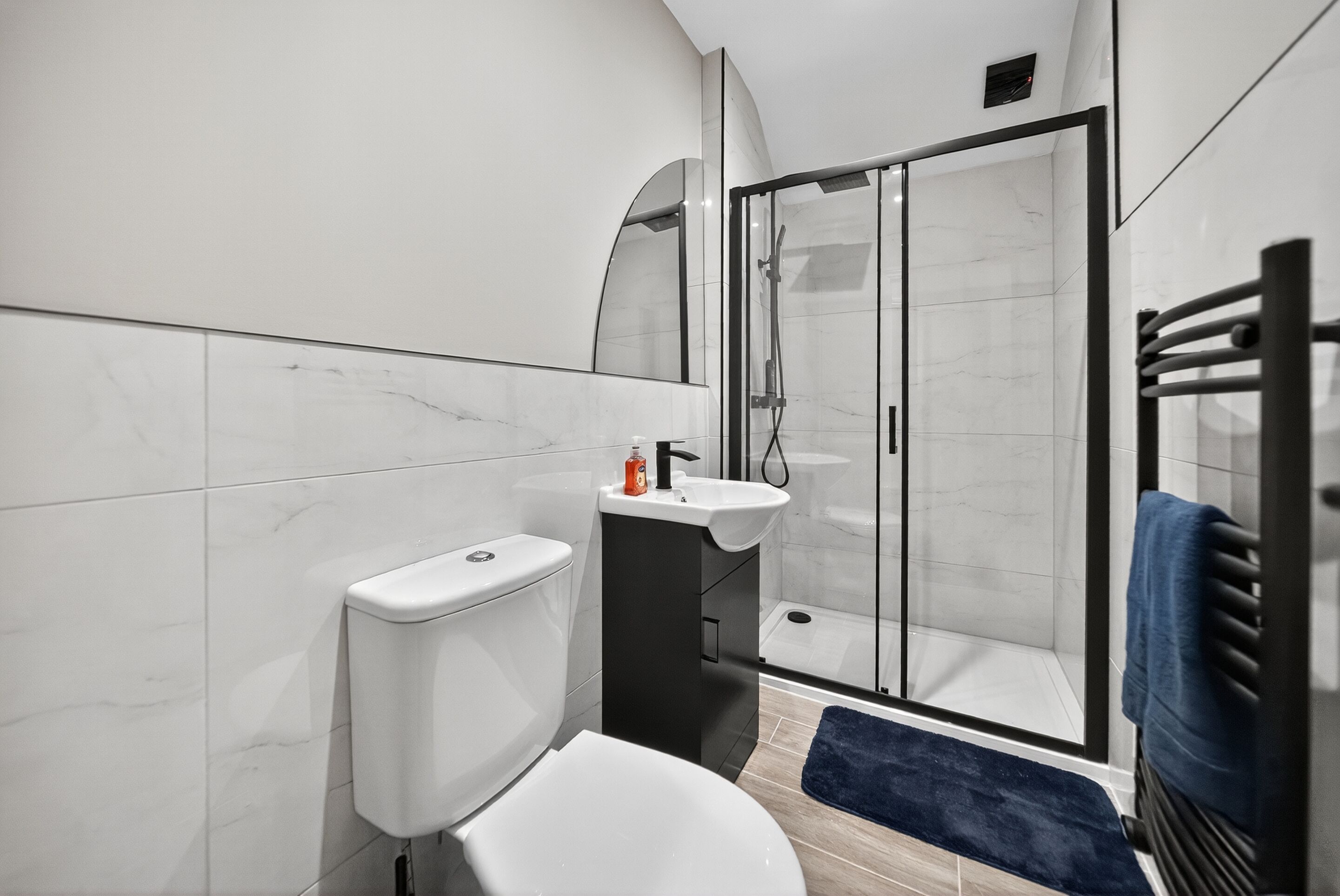 A modern bathroom with a toilet, sink, and glass-enclosed shower.