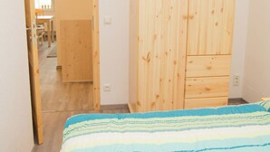 Ein Schlafzimmer mit einem Bett, einem Holzschrank und einer Tür zu einem anderen Raum.