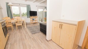 Eine kompakte Küche mit Holzausstattung, einem Esstisch mit Stühlen, einem Fernseher und Blick aus dem Fenster.