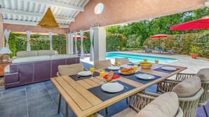 Eine Terrasse im Freien mit Pool, Esstisch und Sitzbereich.