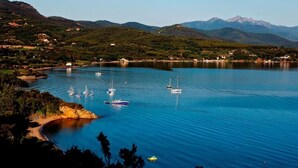 A coastal view with boats on calm waters, surrounded by hills and sparse buildings. - Camping Village Rosselba Le Palme Mobilehome Comfort for 4 persons (Portoferraio)