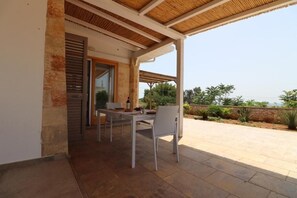 Un patio al aire libre con una mesa y sillas, un muro de piedra y vistas del paisaje.