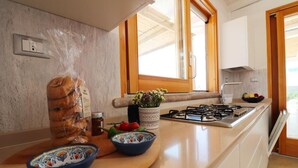 Eine Küche mit Holzarbeitsplatte, einem Brotlaib, einer Obstschale und einem Fenster mit Aussicht.