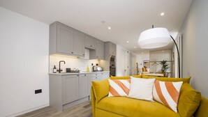 A modern living space with a yellow sofa, kitchen area, and a dining table. - Argyl | Abbey Gate: Studio 4 (Edinburgh)