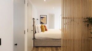 A bedroom with a bed, a radiator, a door, and a plant. - Argyl | Abbey Gate: Studio 4 (Edinburgh)