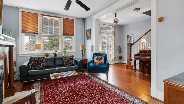 A spacious living room with a dark leather sofa, a blue armchair, and a red patterned rug. - Charming Historic Home-Walk to Carytown-Fence-Pet Friendly-Hotel-grade Towels (Richmond)