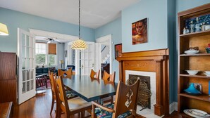 A dining room with a wooden table and chairs, a fireplace, and a bookshelf with various items. - Charming Historic Home-Walk to Carytown-Fence-Pet Friendly-Hotel-grade Towels (Richmond)
