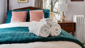 A neatly made bed with teal and pink pillows, a teal quilt, and rolled white towels. - Charming Historic Home-Walk to Carytown-Fence-Pet Friendly-Hotel-grade Towels (Richmond)