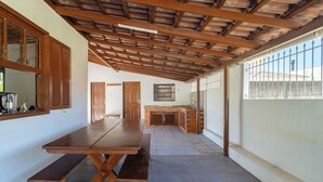 A covered patio with a wooden table and benches, a brick fireplace, and a view of the outside. - House w/ 2 Bedrooms 650 m From the Beach Adu0440 (Florianópolis)