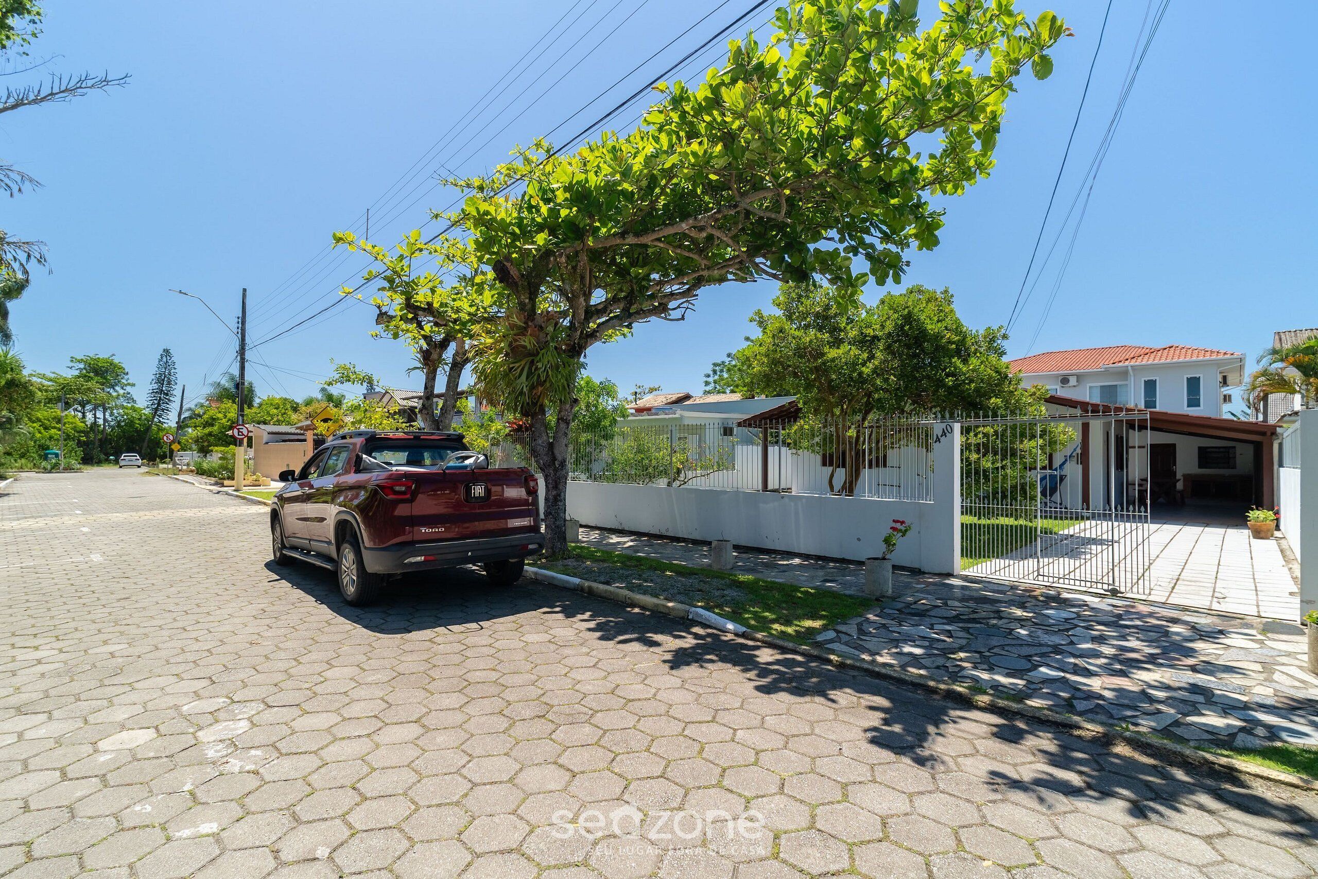 A paved street with a parked car and a tree providing shade.
