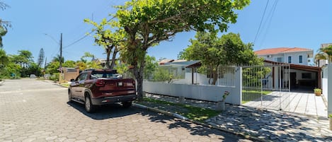 Une rue pavée avec une voiture garée et un arbre qui offre de l’ombre.