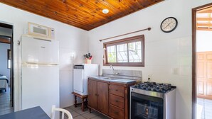 A compact kitchen with a wooden ceiling, a built-in microwave, a sink, a stove, and a clock on the wall. - House w/ 2 Bedrooms 650 m From the Beach Adu0440 (Florianópolis)