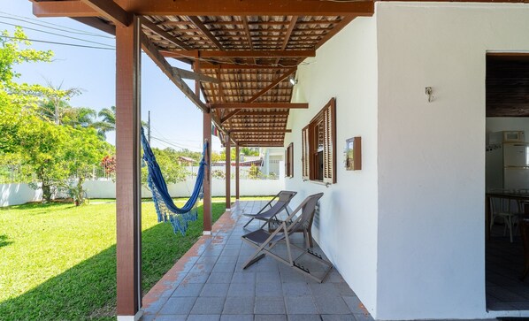 Un'area esterna riparata con un'amaca, due poltrone relax e un patio piastrellato.