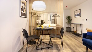 A modern dining area with a round table, black chairs, a white pendant light, and a blue sofa. - Argyl | Abbey Gate: Studio 3 (Edinburgh)
