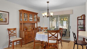 A dining area with a wooden cabinet, a chandelier, and a table set for four. - 3/2 Beautiful Home in Summerhill (The Villages)