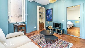 Una sala moderna con sofá, una mesa de centro, una estantería, televisor y un espejo grande.