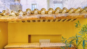 Una habitación pequeña y acogedora con una cama de madera, una pared amarilla y un techo de azulejos.