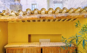 A small, cozy room with a wooden bed, a yellow wall, and a tiled ceiling. - Maison Caractère | In the heart of Lourmarin (Lourmarin)