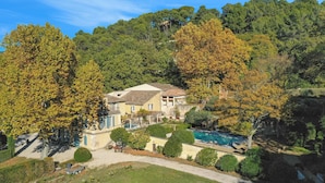 Una villa con piscina, rodeada de árboles y un paisaje montañoso.