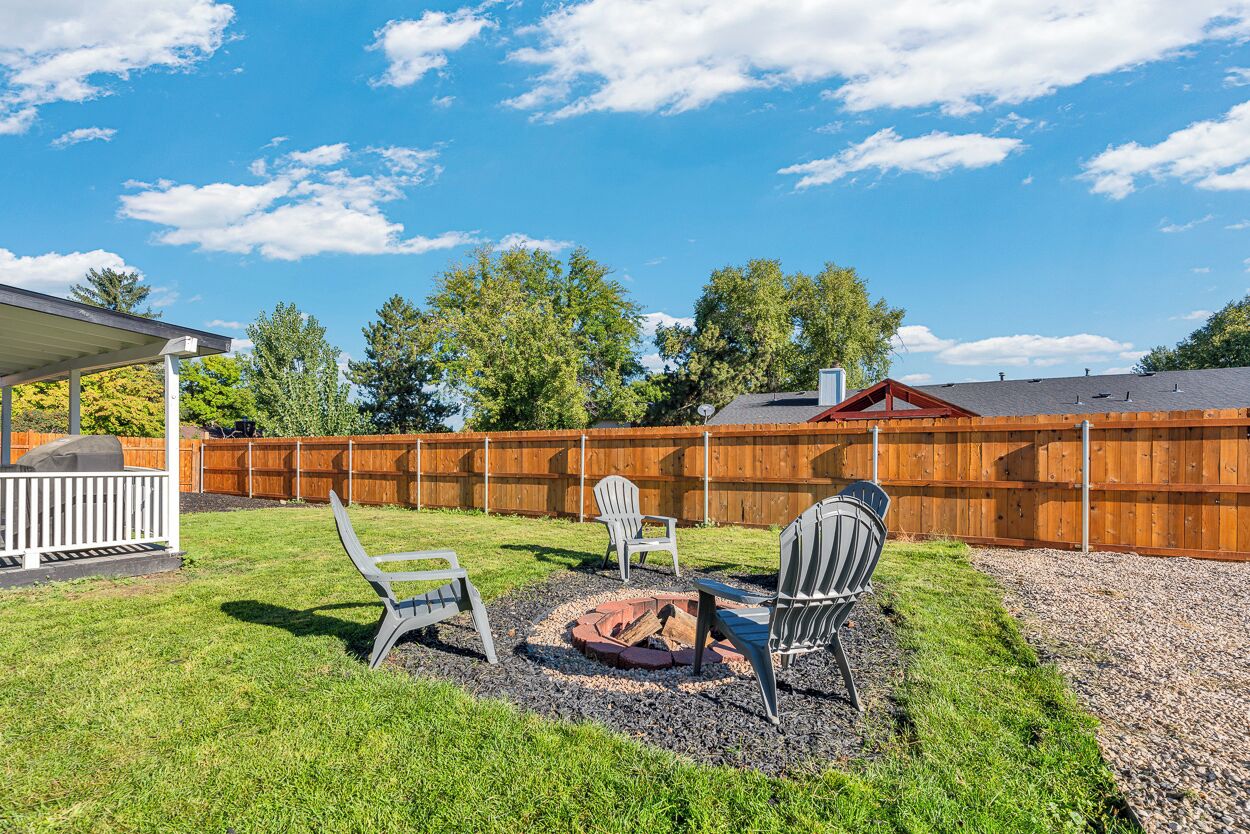 A backyard with a covered patio, a fire pit, and outdoor seating.