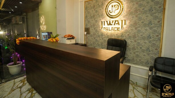 A reception desk with a floral arrangement, a sign for 'JIWAI PALACE', and a potted plant. - Jiwaji Palace (Khatoo)