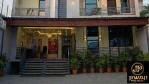 A multi-story building with a modern design, featuring balconies, air conditioning units, and a prominent entrance with steps and potted plants. - Jiwaji Palace (Khatoo)