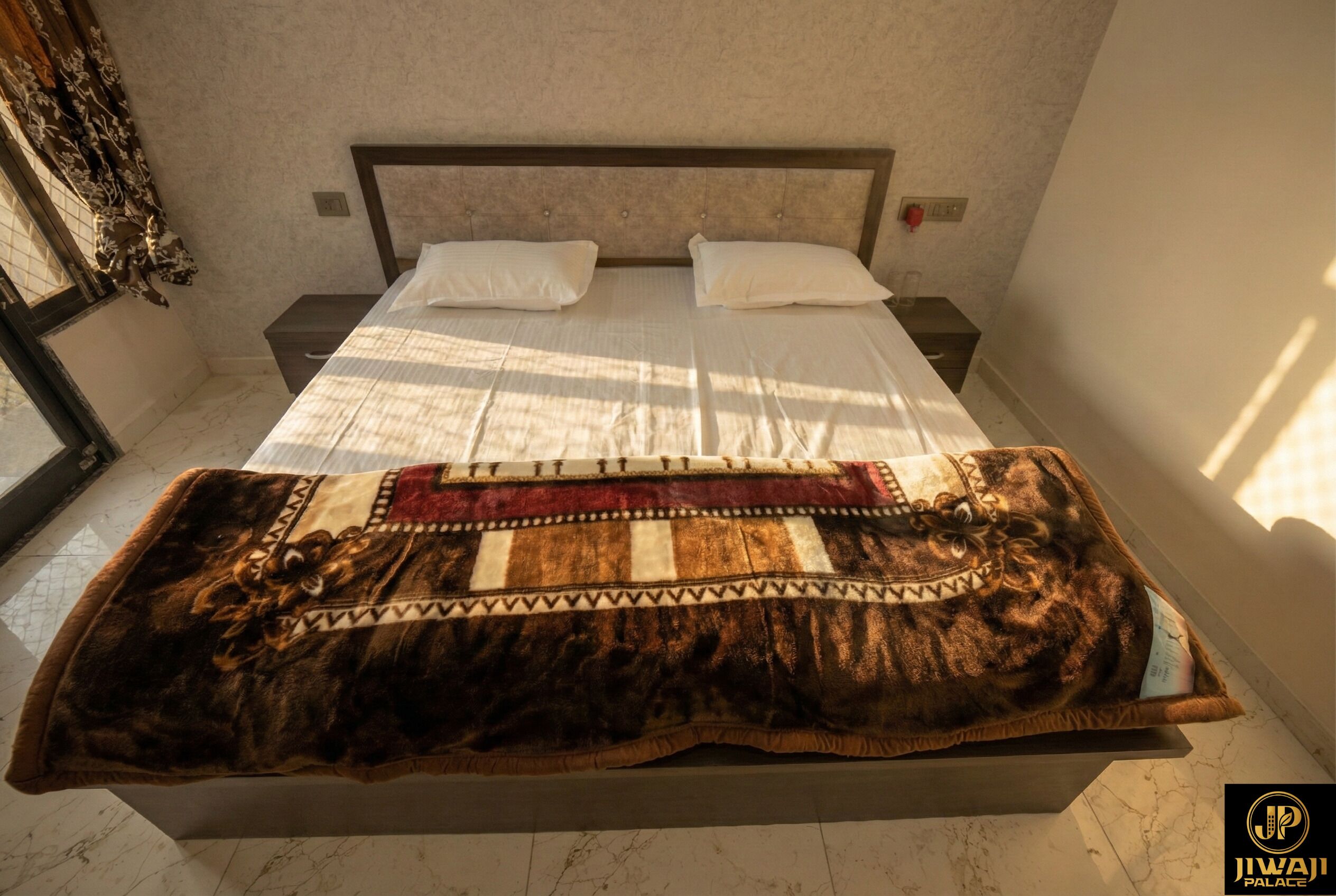 A bed with a patterned blanket, a headboard, and a nightstand with a lamp.