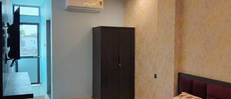 A bedroom with a bed, a wardrobe, an air conditioner, and a window.