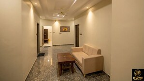 A hallway with a sofa and a wooden table, a ceiling fan, recessed lighting, and a framed picture on the wall. - Jiwaji Palace (Khatoo)