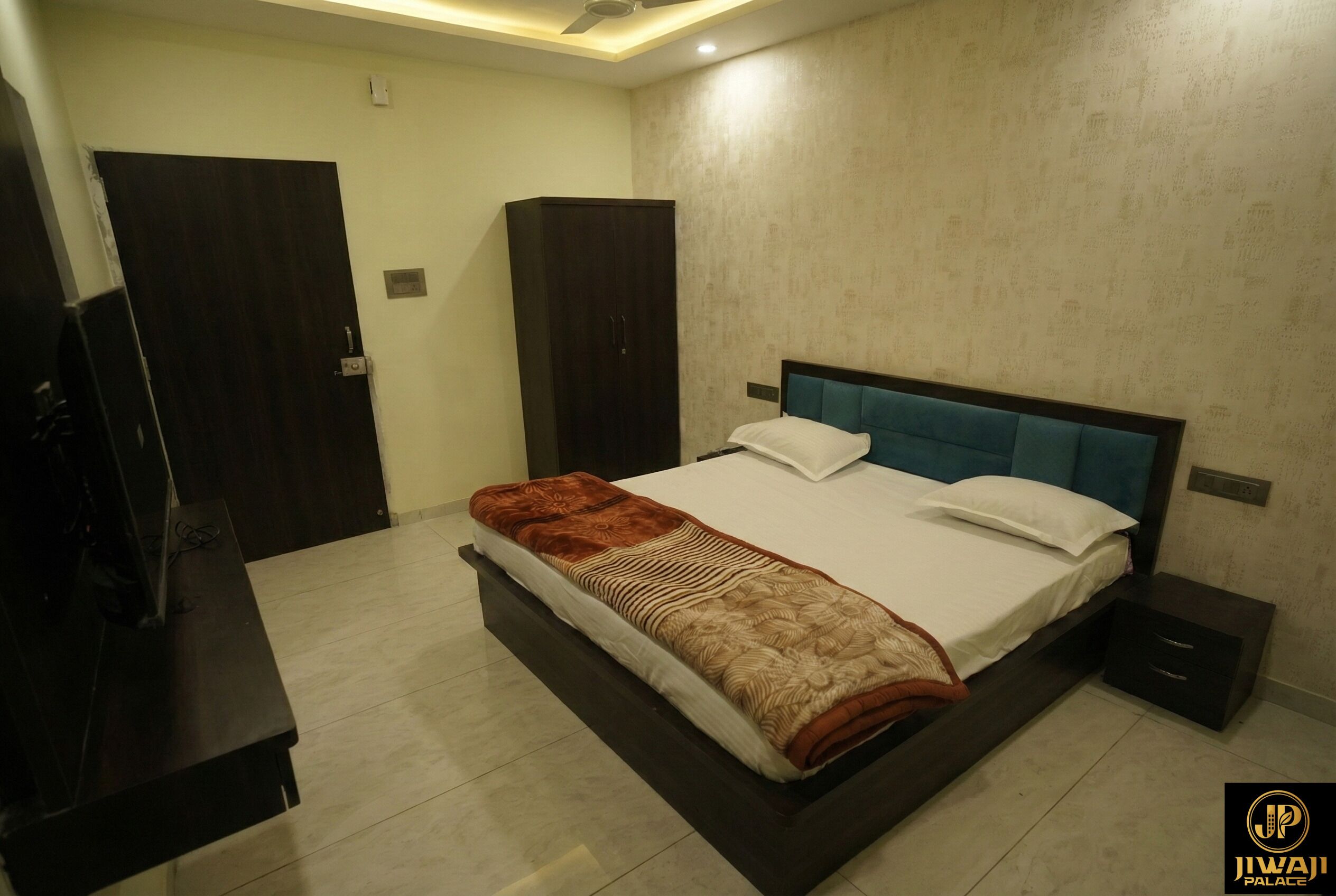Une chambre à coucher comprenant un lit, des tables de chevet, une armoire et un téléviseur.