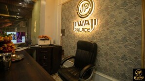 A reception area with a 'Jiwa Palace' sign, a leather chair, a desk with a computer, and a decorative vase. - Jiwaji Palace (Khatoo)
