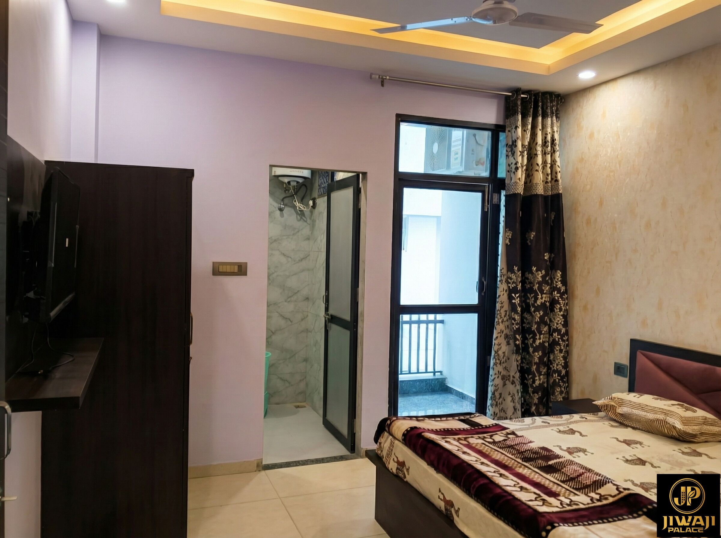 A bedroom with a bed, a television, a door leading to a balcony, and a ceiling fan.