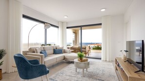 Uma sala de estar moderna com um sofá, cadeiras, uma mesa de centro e uma televisão.