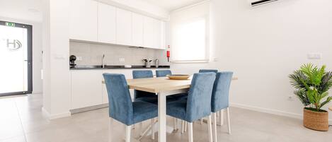A modern kitchen with white cabinets, a wooden dining table, and blue chairs.