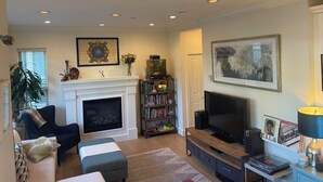 Ein Wohnzimmer mit Kamin, Fernseher, Bücherregal und einer Couch.