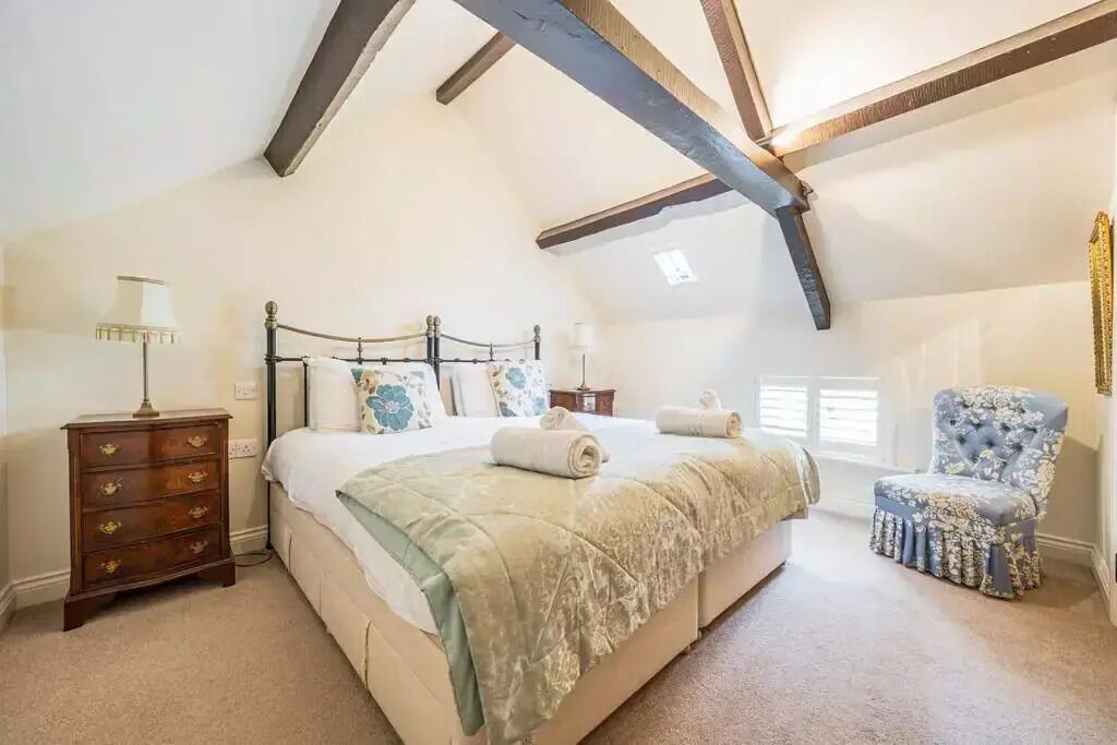 Een slaapkamer met een groot bed, een kaptafel, een stoel en een raam met luiken.