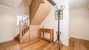 A spacious room with wooden flooring, a wooden staircase, a small wooden table, and a floor lamp. - Beautiful Lake District Cottage With Log Burner (Penrith)