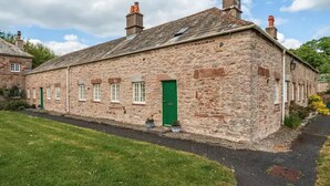 A stone building with a green door, multiple windows, and a paved pathway. - Beautiful Lake District Cottage With Log Burner (Penrith)