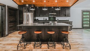 A modern kitchen with a central island, bar stools, stainless steel appliances, and a wooden ceiling. - Sunrise Lookout - Lakefront | Dock | Swim | Fish (Eureka)