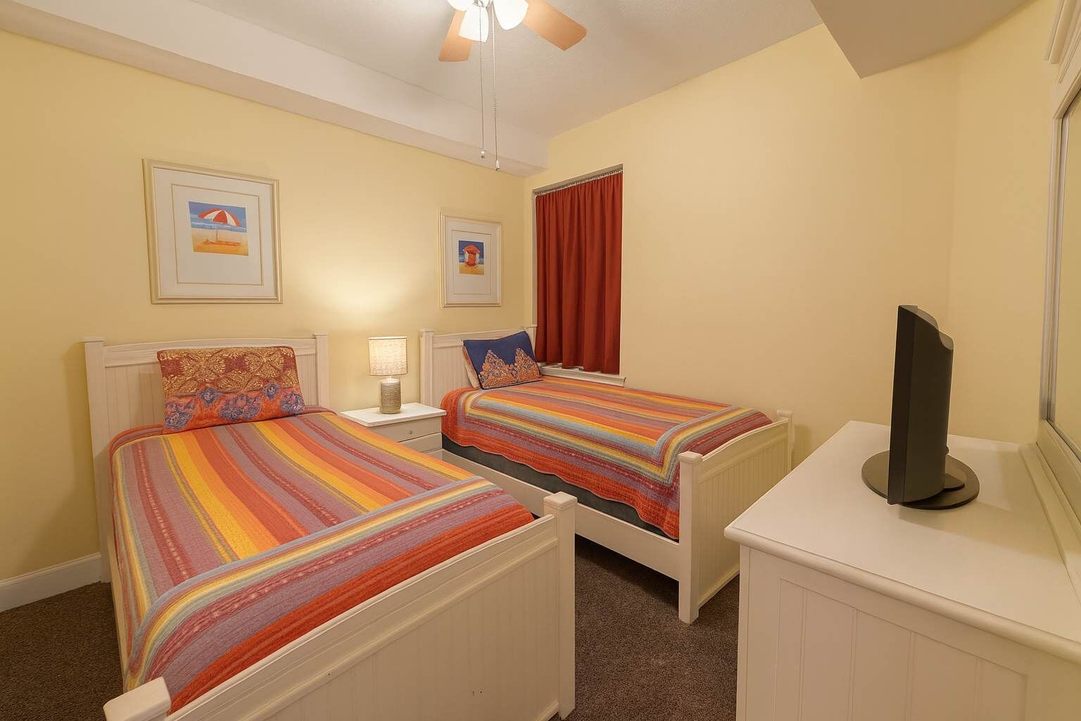 Une chambre d’hôtel avec deux lits, une télévision et des œuvres d’art accrochées aux murs.