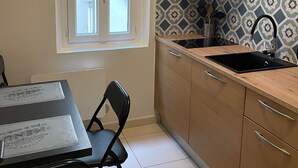 A compact kitchen with a window, a sink, and a dining area with a table and chairs.