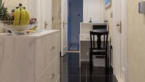 A narrow hallway with a wooden cabinet on the left, a desk with a chair, and a door at the end. - Queen Mary Luxury Rooms Split (Split)